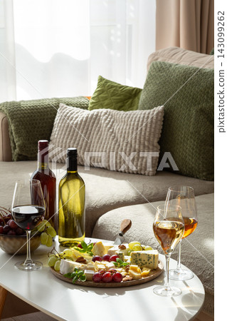 Sophisticated wine and cheese platter arranged elegantly on a table with bottles and glasses 143099262