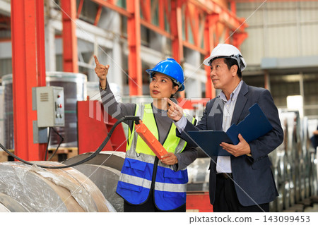 Female technician with remote controller and male manager reviewing clipboard checklist in metal fabrication plant. Female technician with remote controller and male manager reviewing clipboard checklist in metal fabrication plant. 143099453
