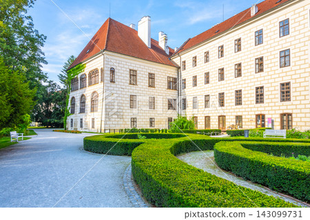 Visitors walk near Trebon Castle in Trebon, Czech Republic. The castle features historic architecture and well-kept gardens. People enjoy the outdoor space and the beauty of this site. Visitors walk near Trebon Castle in Trebon, Czech Republic. The castle features historic architecture and well-kept gardens. People enjoy the outdoor space and the beauty of this site. 143099731