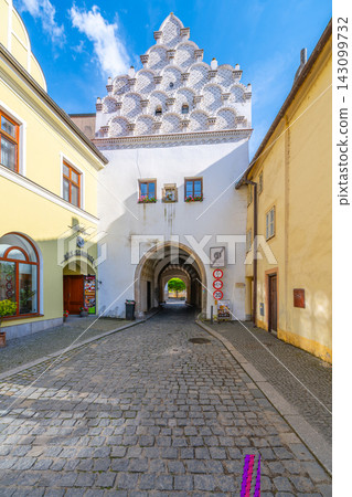 Svinensk Gate is located in Trebon, a town in the Czech Republic. People walk through this historic archway on a clear day, enjoying local shops and sights along the street. 143099732