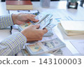 Person Counting US Dollar Bills and Planning Monthly Finance Budget 143100003