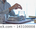 Saving Money Concept. Businessman Putting Coins into Glass Jar Smart Money Habits and Financial Literacy Visual 143100008