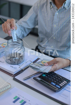Business Man Putting US Dollar Bill into Saving Jar for Financial Planning and Saving Concept. Business Man Putting US Dollar Bill into Saving Jar for Financial Planning and Saving Concept. 143100012