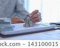 Businessman carefully stacking silver coins on top of documents that feature various business charts and data visualizations. financial planning or investment tracking concept. 143100015