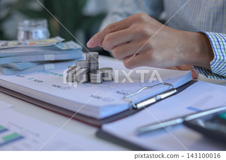 Businessman placing coin on top of coinstacks while engaging in financial planning or investment tracking on office desk Businessman placing coin on top of coinstacks while engaging in financial planning or investment tracking on office desk 143100016