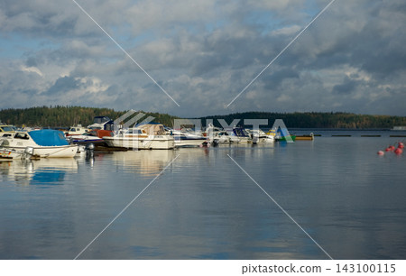Boats Docked at a Calm Lake Pier Under Dramatic Overcast Sky Boats Docked at a Calm Lake Pier Under Dramatic Overcast Sky 143100115
