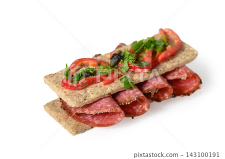 Crispbread sandwich with salami, sliced red pepper, and fresh herbs isolated on white Crispbread sandwich with salami, sliced red pepper, and fresh herbs isolated on white 143100191