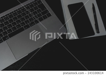 黑色桌面上,筆記型電腦旁邊放著一部智慧型手機、一本筆記本和一支鋼筆。 黑色桌面上,筆記型電腦旁邊放著一部智慧型手機、一本筆記本和一支鋼筆。 143100614