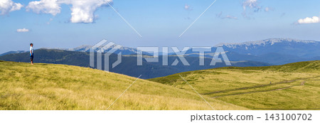 Lonely man hiker standing on a wide hill enjoing mountain view Lonely man hiker standing on a wide hill enjoing mountain view 143100702