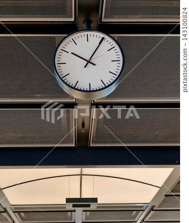 Close-up of an analog wall clock on the ceiling of an airport building. Close-up of an analog wall clock on the ceiling of an airport building. 143100824