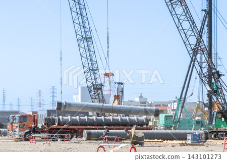 A crane is lifting steel pipe piles from a truck at a foundation construction site for a large building. A crane is lifting steel pipe piles from a truck at a foundation construction site for a large building. 143101273