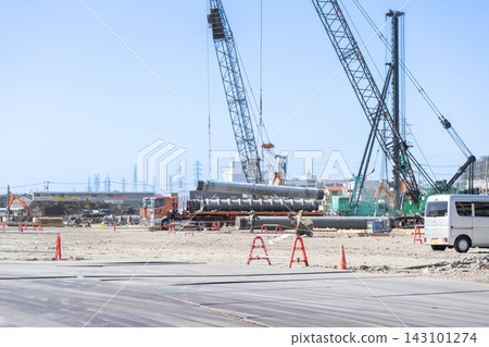 Using a crane to lift steel pipe piles at a foundation construction site for a large building. Using a crane to lift steel pipe piles at a foundation construction site for a large building. 143101274