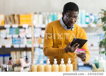 Man in glasses scans code on package of pills to check expiration date Man in glasses scans code on package of pills to check expiration date 143101502