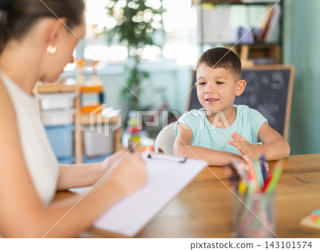 Child psychologist fills out questionnaire and interviews boy in kindergarten. Child psychologist fills out questionnaire and interviews boy in kindergarten. 143101574