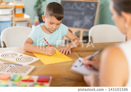 Little boy tracing figures on yellow sheet during psychological test Little boy tracing figures on yellow sheet during psychological test 143101586