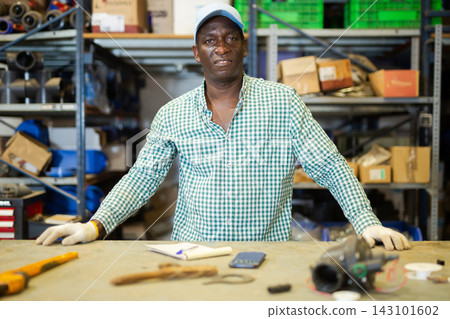 Warehouse worker standing at table in workshop 143101602