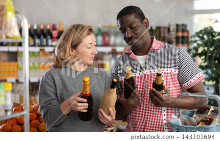 African man with European wife hold bottle and choose alcohol, wine or beer bottle in store African man with European wife hold bottle and choose alcohol, wine or beer bottle in store 143101693