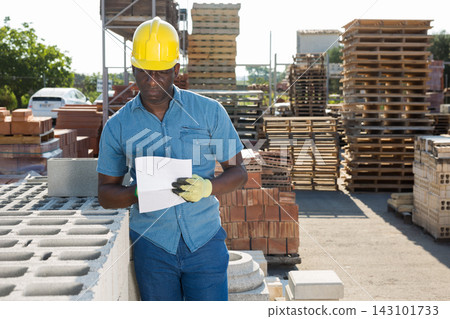 Worker filling documentation beside hollow block stack outdoors Worker filling documentation beside hollow block stack outdoors 143101733