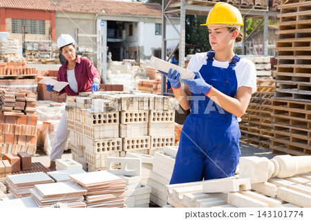 Female builders in outdoor concrete material storage Female builders in outdoor concrete material storage 143101774