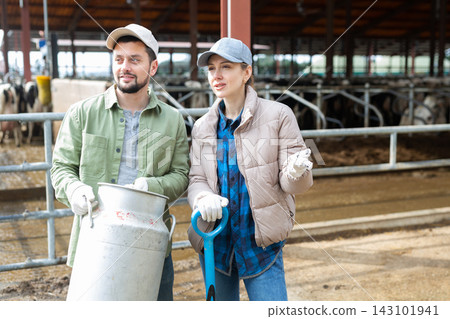 Man and woman dairy farm workers talking at cow barn 143101941