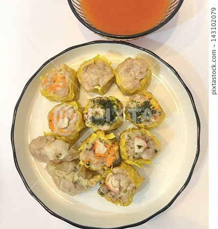 Shumai shrimp with sauce, Steamed shrimp dumplings dim or dim sum and vegetable on wooden table, Cantonese Dimsum food cuisine for breakfast, Chinese traditional food. Shumai shrimp with sauce, Steamed shrimp dumplings dim or dim sum and vegetable on wooden table, Cantonese Dimsum food cuisine for breakfast, Chinese traditional food. 143102079