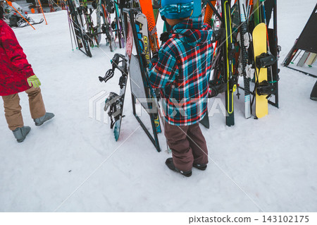 A 12-year-old boy leaning his skis against the ski rack. A 12-year-old boy leaning his skis against the ski rack. 143102175