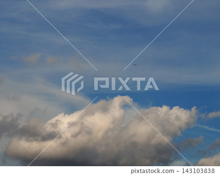 An airplane flying above white cumulonimbus clouds 143103838