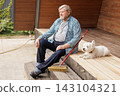 Senior man sits beside a broom on a wooden porch while his dog rests nearby, illustrating home upkeep, companionship, and active retirement living. 143104321