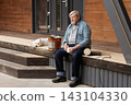 Man sands wooden terrace steps beside a container of protective oil, preparing outdoor decking for maintenance, restoration, and weather-resistant finishing. 143104330