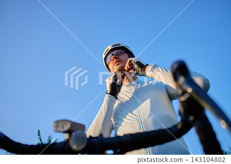 Cyclist fastening helmet before bike training Cyclist fastening helmet before bike training 143104802