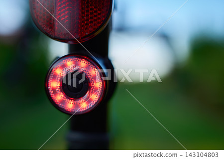 Red bicycle rear light glowing outdoors Red bicycle rear light glowing outdoors 143104803