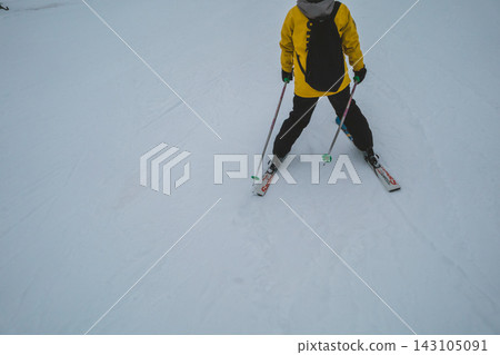 一名身穿黃色滑雪服的女子正在滑雪下山。 143105091
