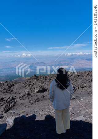 Young man observes the vast landscape from the summit of Mount Etna on the island of Sicily, Italy. Young man observes the vast landscape from the summit of Mount Etna on the island of Sicily, Italy. 143105246