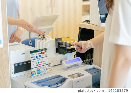 A woman paying with a credit card at the reception desk of a dental clinic. A woman paying with a credit card at the reception desk of a dental clinic. 143105279