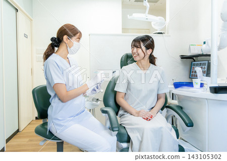 A female patient receiving treatment at a dental clinic and the dentist A female patient receiving treatment at a dental clinic and the dentist 143105302
