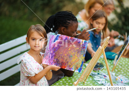 Girl proudly showing colorful painting during outdoor art class Girl proudly showing colorful painting during outdoor art class 143105435