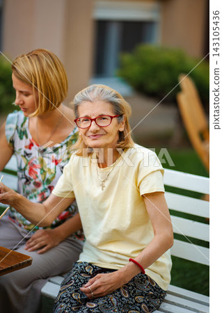 Senior woman smiling with adult daughter outdoors Senior woman smiling with adult daughter outdoors 143105436