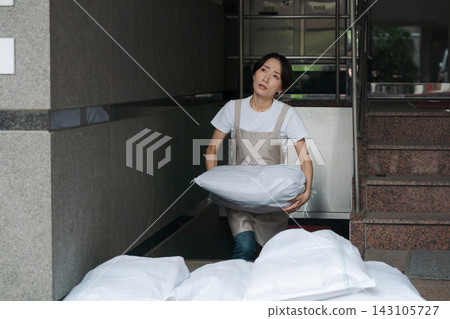一名婦女正在堆放沙袋,為防洪做準備。 一名婦女正在堆放沙袋,為防洪做準備。 143105727