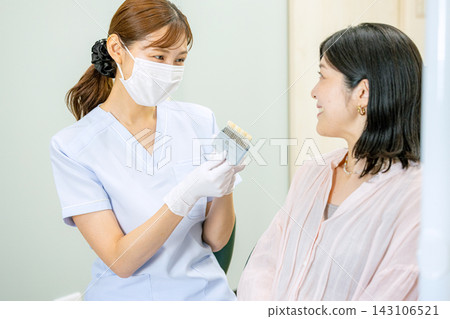 一位女士正在牙醫診所與牙齒保健員交談。 一位女士正在牙醫診所與牙齒保健員交談。 143106521