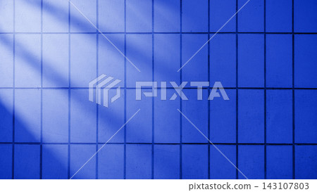 A dark blue tiled wall background with light rays cast across the surface, creating an abstract and textured pattern for modern design projects. Blue textured background A dark blue tiled wall background with light rays cast across the surface, creating an abstract and textured pattern for modern design projects. Blue textured background 143107803