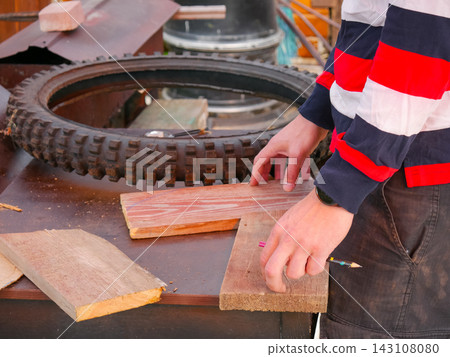 Hand marking wooden plank with pencil on workbench Hand marking wooden plank with pencil on workbench 143108080