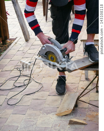 Man cutting wooden board with circular saw outdoors Man cutting wooden board with circular saw outdoors 143108118