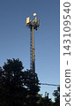 Tall telecommunication tower and 5G cellular antennas against a clear blue sky. 143109540