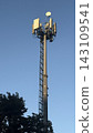 Tall telecommunication tower and 5G cellular antennas against a clear blue sky. 143109541