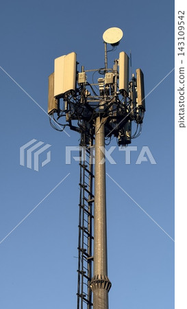 Close-up of tall telecommunication tower and 5G cellular antennas against a clear blue sky. Close-up of tall telecommunication tower and 5G cellular antennas against a clear blue sky. 143109542