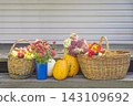 Autumn gardening still life; wicker baskets with ripe apples, squashes and bouquet of autumn flowers 143109692