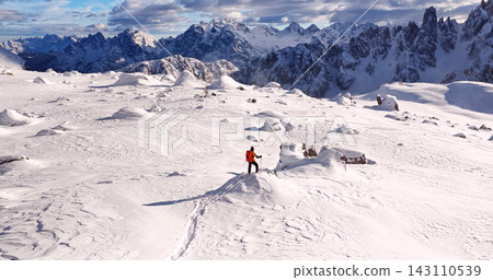 Ski mountaineer crossing a snowy ridge in the Dolomites with dramatic alpine peaks and blue sky in the background, capturing winter adventure and breathtaking mountain landscape. Ski mountaineer crossing a snowy ridge in the Dolomites with dramatic alpine peaks and blue sky in the background, capturing winter adventure and breathtaking mountain landscape. 143110539
