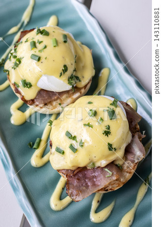 Eggs Benedict breakfast food on white table at modern restaurant cafe outdoors Eggs Benedict breakfast food on white table at modern restaurant cafe outdoors 143110881