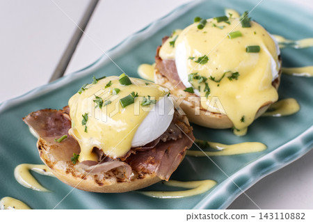 Eggs Benedict breakfast food on white table at modern restaurant cafe outdoors Eggs Benedict breakfast food on white table at modern restaurant cafe outdoors 143110882