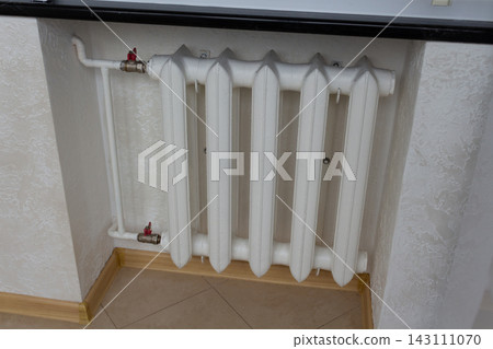 White home heating battery section mounted under a window sill on a textured wall White home heating battery section mounted under a window sill on a textured wall 143111070